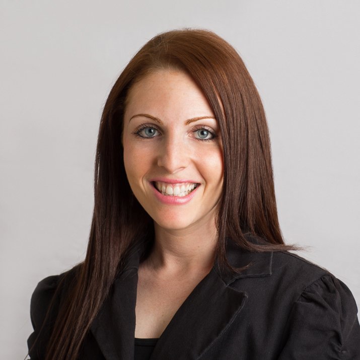 Corporate headshot of a smiling woman with auburn hair on a light background