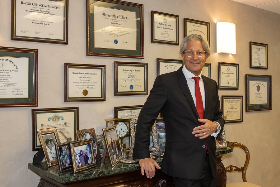 Physician photographed on location in his own office, in front of his framed credentials