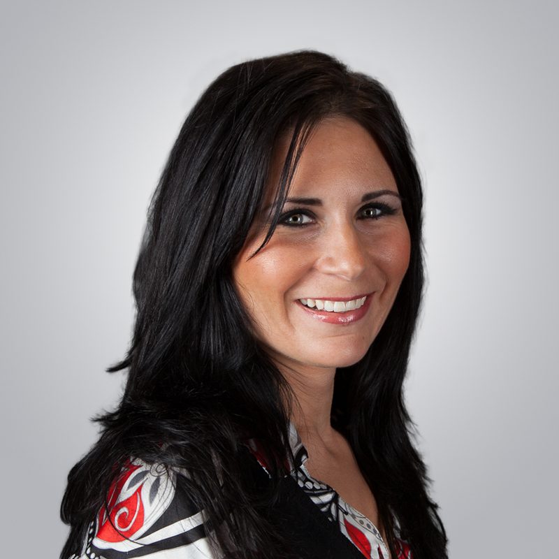 Real estate agent headshot of a smiling woman with long dark hair in a patterned top