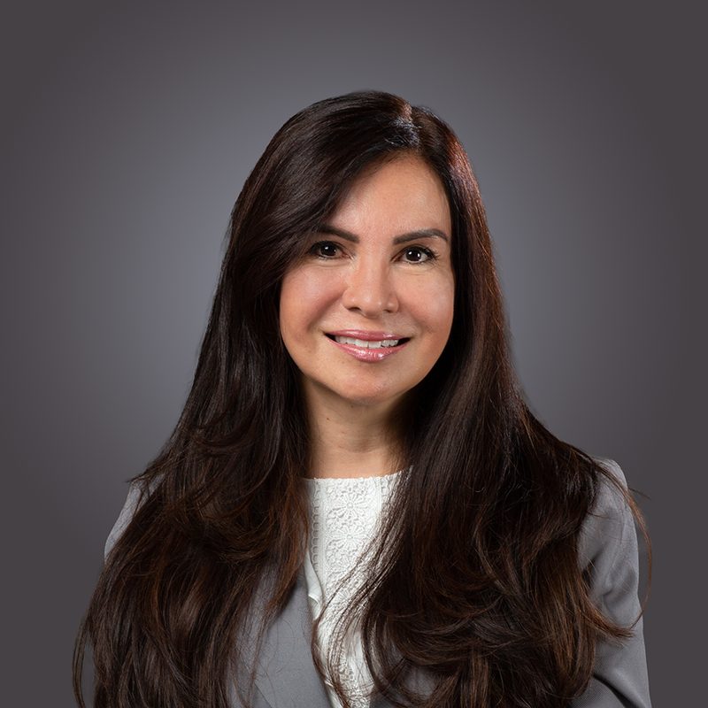Real estate agent headshot of a smiling woman with long dark hair in a grey jacket